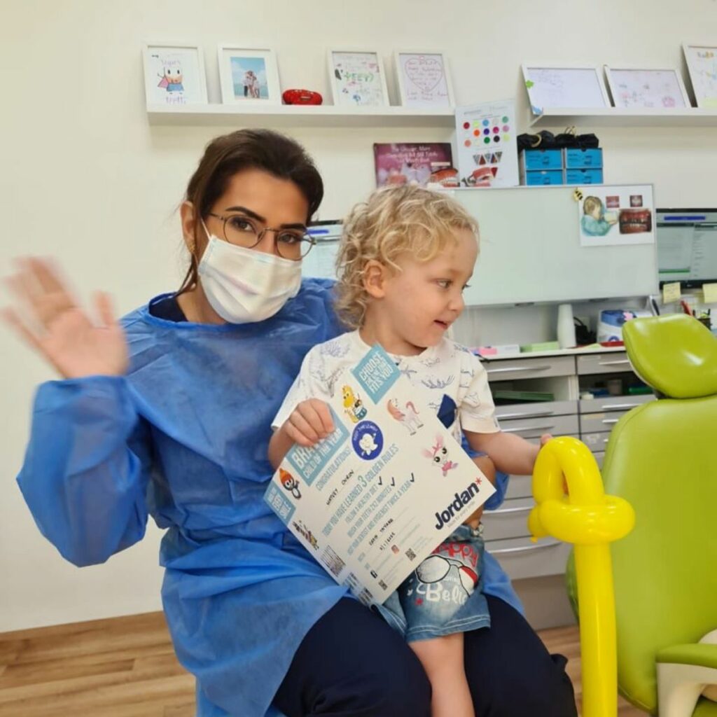 Dr. Rafif Tayara, dentist for kids and early ortho in Dubai, with a toddler patient after a check-up