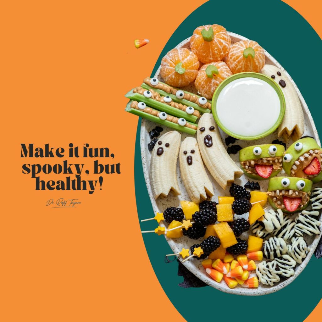 Spooky but healthy Halloween platter for kids with ghost bananas, clementine pumpkins, apple monster mouths and fruit skewers