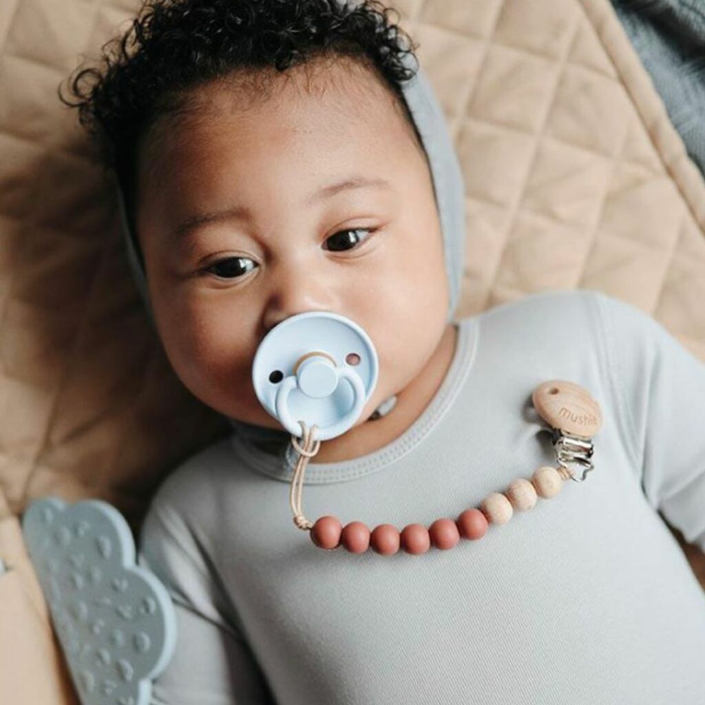 Baby with a bulky, oversized pacifier — the wrong pacifier shape according to a pediatric dentist in Dubai